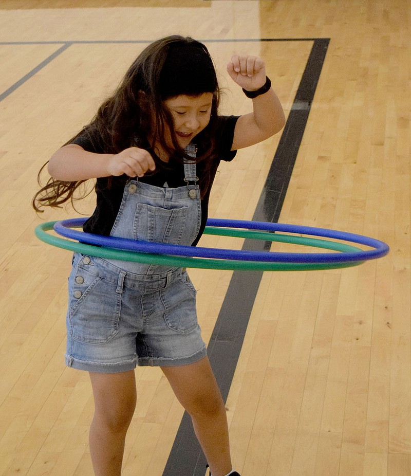 Westside Eagle Observer/MIKE ECKELS
Lainey Hernandez shows off her hula hoop skills as she spins up a pair of the popular toys during a break in the Lady Bulldog volleyball practice in the gym at Decatur Middle School June 20. The WHAM-O device is still as popular in the 21st century as it was in 1958 when it first hit the American toy market.