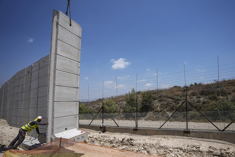 Workers place sections of 30-foot-tall concrete wall to replace a border fence between the northern West Bank and Israel, near the Arab village of Salem, on Wednesday, June 22, 2022. The Israeli defense ministry said Wednesday that it had started construction on a section of separation barrier in the northern West Bank after months of military raids in the area following a string of deadly attacks on Israelis by Palestinians. The ministry announced that it began work on a 28-mile stretch of wall to replace fencing installed 20 years earlier. (AP Photo/Ariel Schalit)