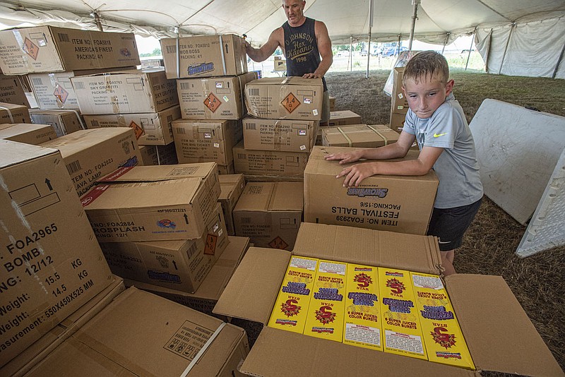 Lonnie Roberson, manager of Super Samâ€™s Fireworks, and his 7-year-old son Rudy Roberson, both of Searcy, unpack boxes of fireworks on Wednesday, June 22, 2022, at their fireworks stand along US-71 in Fort Smith. With the arrival of a shipment of fireworks on Wednesday, the Roberson family, including mother Candace and 4-year-old Carly, were spending the day setting up tables and products to begin selling them as soon as possible ahead of Independence Day next Monday. Visit nwaonline.com/220623Daily/ for today's photo gallery.
(NWA Democrat-Gazette/Hank Layton)