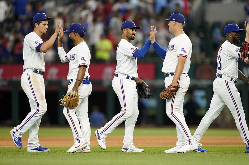 Texas Rangers' Corey Seager, Ezequiel Duran, Marcus Semien, Nathaniel Lowe and Adolis Garcia, from left, celebrate the team's 4-2 win in a baseball game against the Philadelphia Phillies, Wednesday, June 22, 2022, in Arlington, Texas. (AP Photo/Tony Gutierrez)