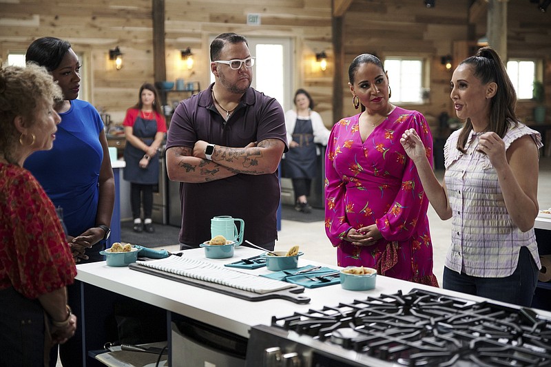 Judges Tiffany Derry (second from left), Graham Elliot, host Alejandra Ramos and judge Leah Cohen gather around a contestant’s station in a scene from the competition series “The Great American Recipe.” (PBS via AP)