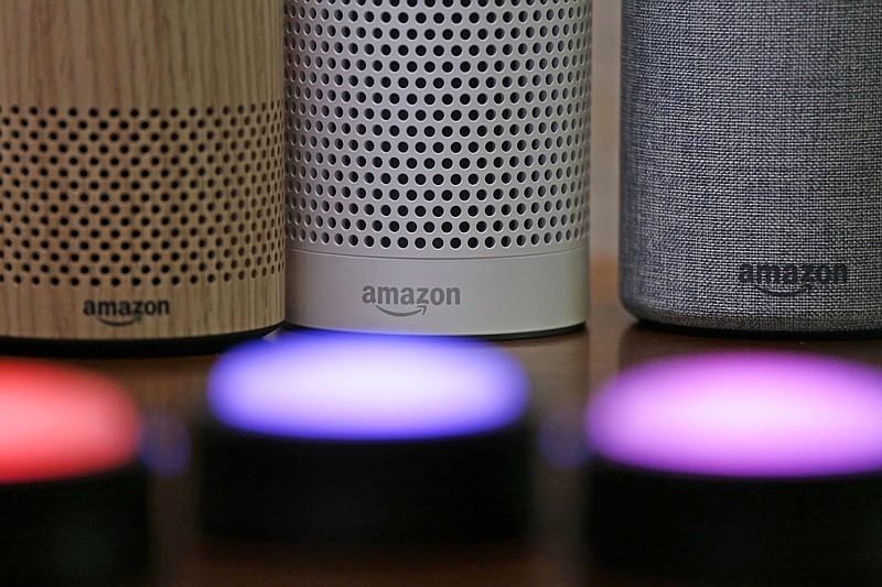 FILE - Amazon Echo and Echo Plus devices, behind, sit near illuminated Echo Button devices during an event by the company in Seattle on Sept. 27, 2017. Amazon’s Alexa might soon replicate the voice of family members - even if they’re dead. The capability, unveiled at Amazon’s Re:Mars conference in Las Vegas Wednesday, June 22, 2022, is in development and would allow the virtual assistant to mimic the voice of a specific person based on less than a minute of provided recording. (AP Photo/Elaine Thompson, File)