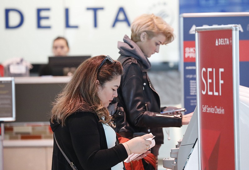 FILE - Travelers use the Delta airlines self check-in at Love Field in Dallas, Nov. 27, 2019. Delta Air Lines will be able to continue operating flights at Dallas Love Field for another six years, under a settlement approved by the city council. The agreement, which passed without debate this week, appears to end a long court fight over gates at the city-owned airport near downtown Dallas that is dominated by Southwest Airlines. (AP Photo/LM Otero, file)