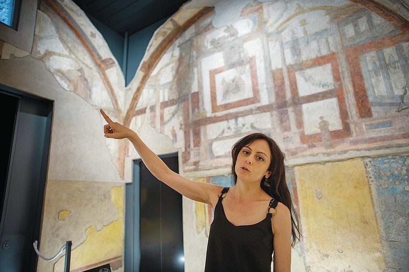 Archaeologist Silvia Fortunati describes to journalists the frescoes coming from the sacellum, a small votive chapel, of a two-story home, or "Domus," dating from around 134-138 AD that was partially destroyed to make way for the construction of the Caracalla public baths, which opened in 216 AD, are on display at the Caracalla archaeological park in Rome, Thursday, June 23, 2022. The frescoed ceiling and walls of a domestic temple honoring Greco-Roman and Egyptian religious deities and believed to have belonged to a wealthy merchant family were first discovered in the mid-19th century about 10 meters (yards) underneath the current ground level of the baths, had been briefly exhibited but has been closed to the public for 30 years. (AP Photo/Domenico Stinellis)