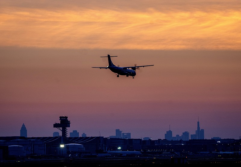 FILE - An aircraft lands at the international airport in Frankfurt, Germany, before sunrise on Tuesday, June 21, 2022. After two years of pandemic restrictions, travel demand is back with a vengeance but airlines and airports that slashed jobs during the depths of the COVID-19 crisis are struggling to keep up. With the busy summer tourism season underway in Europe, passengers are encountering chaotic scenes at airports, including lengthy delays, canceled flights and headaches over lost luggage. (AP Photo/Michael Probst, File)