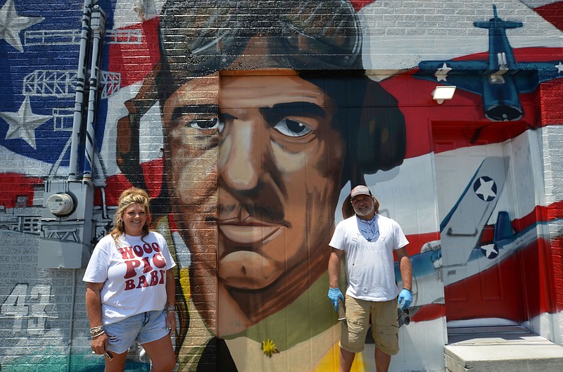 Candace McCollum (left) and mural artist Jason White stand in front of the newly completed portrait of Vice Admiral Jimmy Thach, Fordyce native and inventor of the flight maneuver the “Thach Weave.” (Special to The Commercial/Richard Ledbetter)