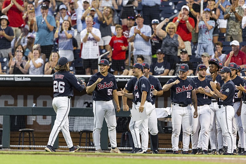 Mississippi pitcher Hunter Elliott (left) walks to his teammates and cheering fans after being relieved in the seventh inning Monday against Arkansas during the men's College World Series in Omaha, Neb. (Associated Press)