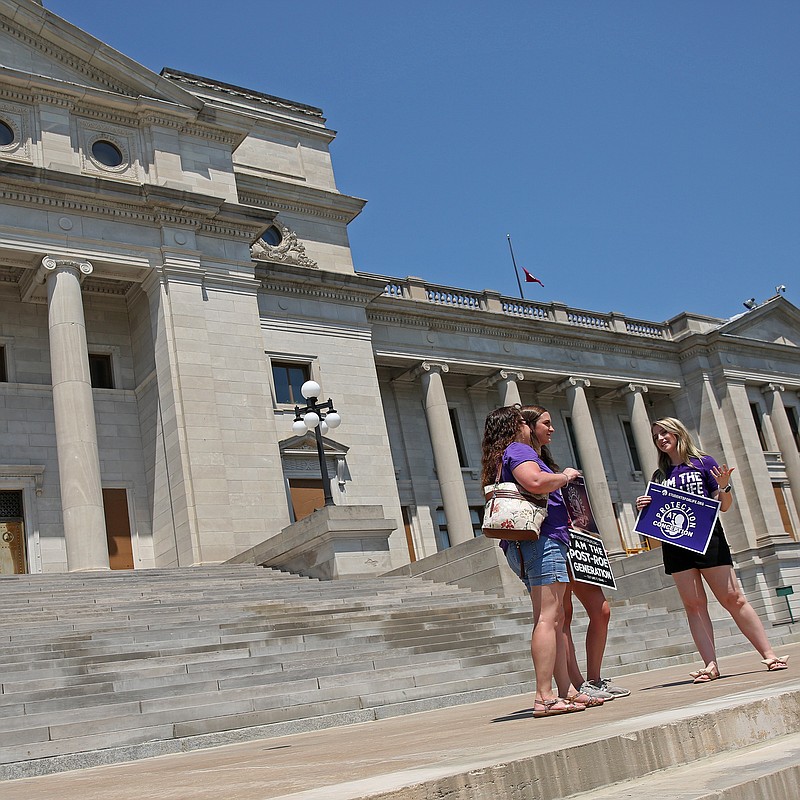 From left: Pro-life demonstrators Kim Gentry (from left), Emily Gentry and Kelsey Muse stand on the steps of thestate Capitol on Saturday, June 25, 2022 during an event marking the Supreme Court's decision to overturn the landmark Roe v. Wade decision last week. (Arkansas Democrat-Gazette/Colin Murphey)