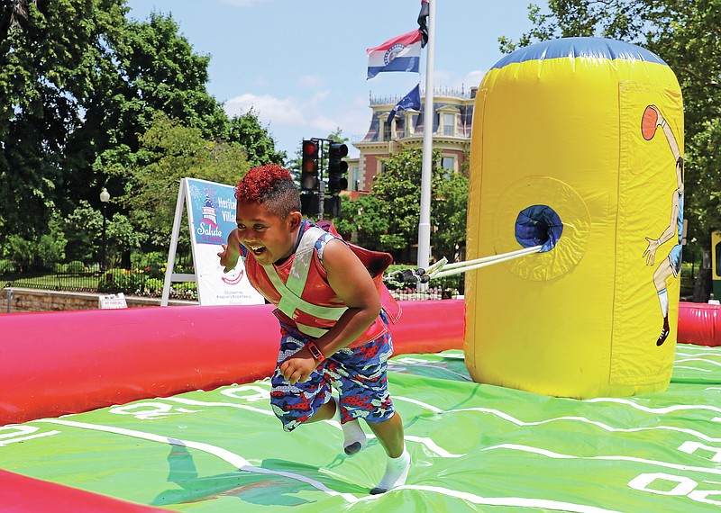 Avrey Johnson, 8, powers his way toward the end zone Saturday afternoon, July 3, 2021, in the carnival area at the Salute to America celebration in downtown Jefferson City. Johnson got off to a fast start and was able to gradually make his way to touching the wall of the inflatable game. (Jason Strickland/News Tribune file photo)