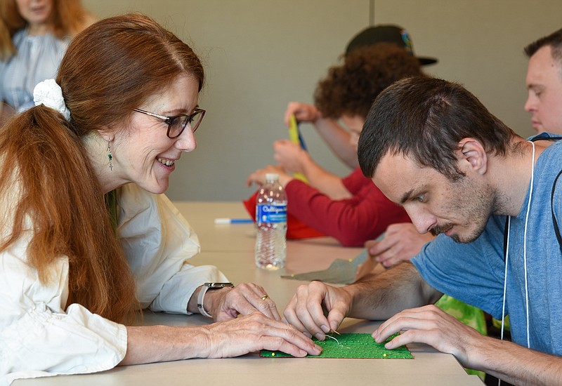 Pam Robinson, left, works with Ryan O'Neal Monday, June 27, 2022, to sew a pattern on a quilt block. Robinson is a member of the James River Mountain Man Association and part of a group helping to put on activities for participants in this week's SOMO Sports Camp in Jefferson City. The camp features more than a dozen activities in which campers can take part. O'Neal is from Raytown, Mo., and was doing well as he sewed a star shape on the material. (Julie Smith/News Tribune photo)