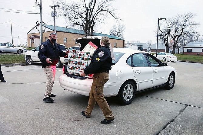 Lt. Jason Barnes, left, and Det. Crystal Kent load gifts into the vehicle of a Shop with a Hero participant. Due to the pandemic in 2020, Fulton police shopped on children's behalf and hosted a drive-thru event, rather than going on a joint shopping trip to Walmart. (FULTON SUN FILE PHOTO)