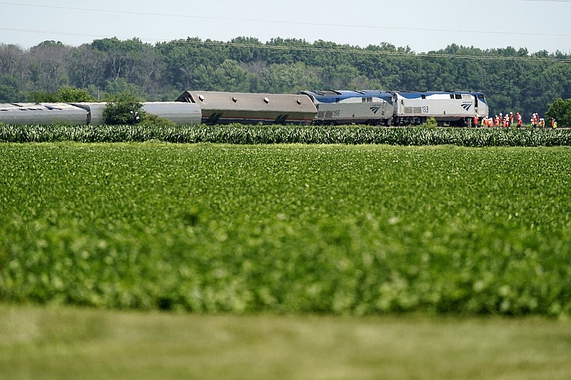 Workers gather at the front of a derailed Amtrak train Tuesday, June 28, 2022, near Mendon, Mo. The Chicago-bound train derailed Monday after striking a dump truck. (AP Photo/Charlie Riedel)