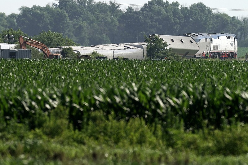 Workers gather near a derailed Amtrak train Tuesday, June 28, 2022, near Mendon, Mo. The train derailed after hitting a dump truck Monday killing the truck driver and other people on the train and injuring several dozen other passengers on the Chicago-bound train. (AP Photo/Charlie Riedel)