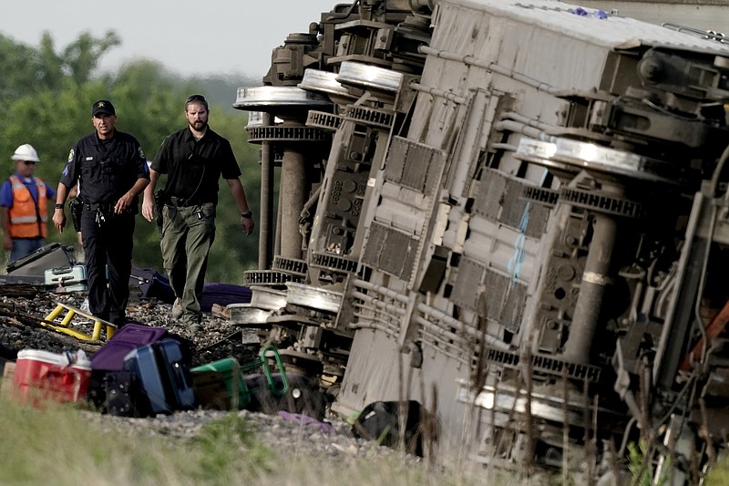 Law enforcement personnel inspect the scene of an Amtrak train which derailed after striking a dump truck Monday, June 27, 2022, near Mendon, Mo. (AP Photo/Charlie Riedel)