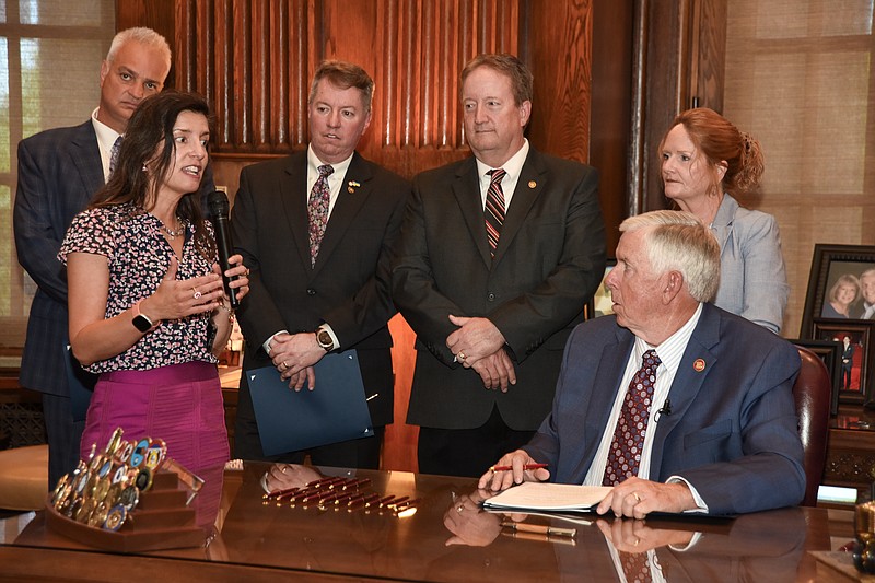 Mayor Carrie Tergin, second from left, talks about what the passage and signing of HB 1606 will mean for Jefferson City regarding the acquisition of properties by the city, most notably the vacant properties on E. Capitol Avenue. Missouri Gov. Mike Parson, seated at right, hosted a bill signing Wednesday, June 29, 2022, in his Capitol office during which he signed into law several pieces of legislation passed during this most recent session. Standing in the back row are legislators who worked on this particular bill and from left are representatives Bruce DeGroot, Michael O'Donell, Bill Falkner and Donna Baringer. (Julie Smith/News Tribune photo)