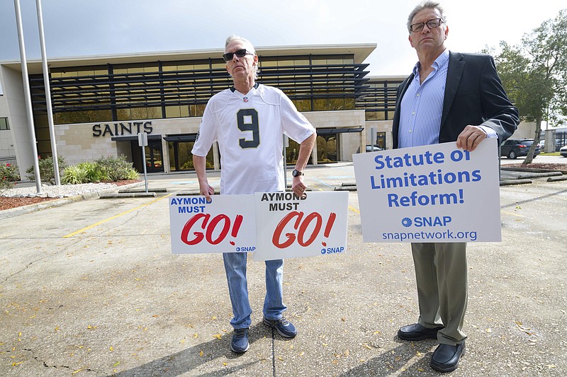 FILE - Members of SNAP, the Survivors Network of those Abused by Priests, including Richard Windmann, left, and John Gianoli, right, hold signs during a conference in front of the New Orleans Saints training facility in Metairie, La., Wednesday Jan. 29, 2020.  The FBI has opened a widening investigation into sex abuse in the Roman Catholic Church in New Orleans going back decades, a rare federal foray into such cases looking specifically at whether priests took children across state lines to molest them, officials and others familiar with the inquiry told The Associated Press.   (AP Photo/Matthew Hinton, File)