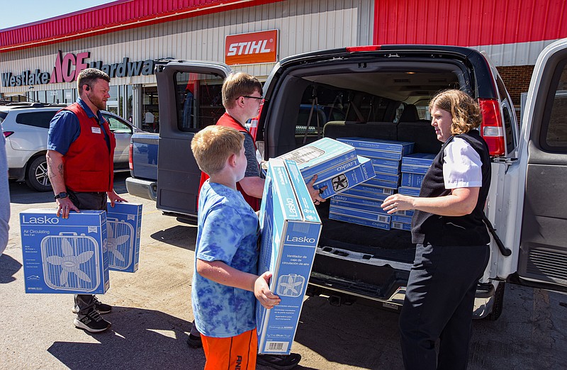 Julie Smith/News Tribune
James Hayes, left, carries box fans to his Westlake Ace Hardware co-worker Devon Bailey, at back of van, to place inside as Nolan Windell, 9, middle, hands his mother, Major Sarah Windell, a box fan he picked from the cart. Once again Westlake came through with fans for the Salvation Army who next week will begin distribution to those in need. In total Ace Hardware collected donations to purchase 91 fans, of which over half were picked up Thursday by Windell and her sons.