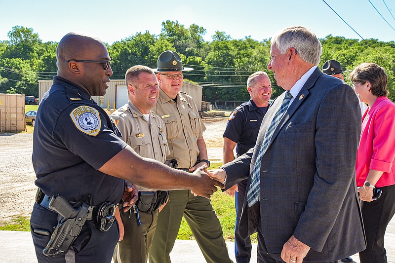 Following Thursday's media event to announce the construction of a multi-agency health lab, Missouri Gov. Mike Parson stopped to visit with members of local law enforcement in attendance. Here, he is shown shaking hands with  Lincoln University Police Chief Gary Hill, while Callaway County Sheriff Clay Chism, Cole County Sheriff John Wheeler and look on. Shown in the background is Jefferson City Police Chief Eric Wilde visiting with Missouri Public Safety Director Sandra Karsten, behind Parson. (Julie Smith/News Tribune photo)