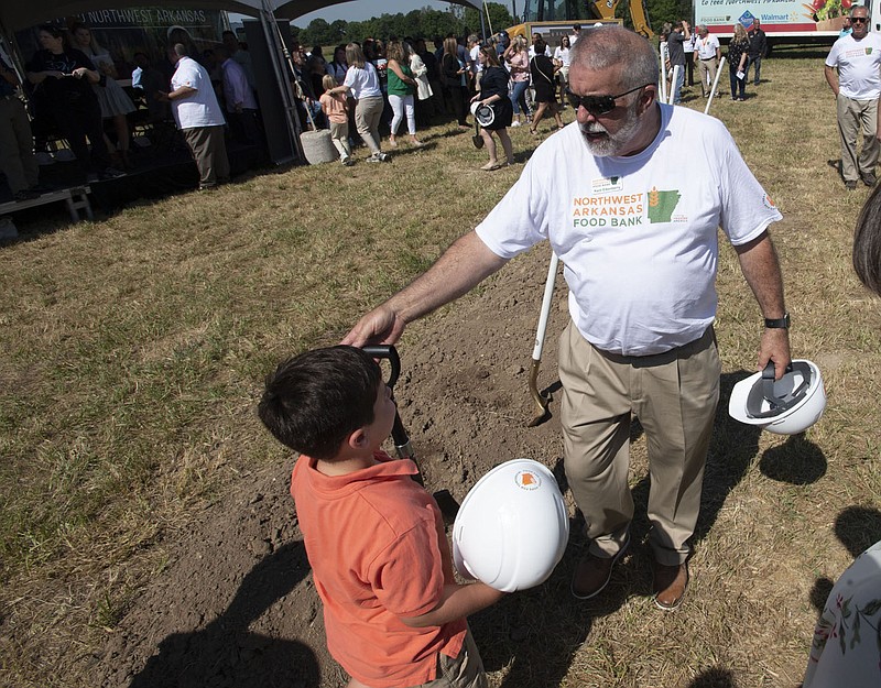 Kent Eikenberry, President and CEO of the Northwest Arkansas Food Bank, gifts a shovel Thursday June 30, 2022 to Alexander Cardarelli, 6, after a groundbreaking ceremony for a new facility in Lowell. The new campus will house a new distribution facility and launch new programs to increase annual distribution and improve access to food across its four-county service area. Cardarelli's mom is on the food bank's board of directors.  Visit nwaonline.com/220701Daily/ for daily galleries.  (NWA Democrat-Gazette/J.T. Wampler)