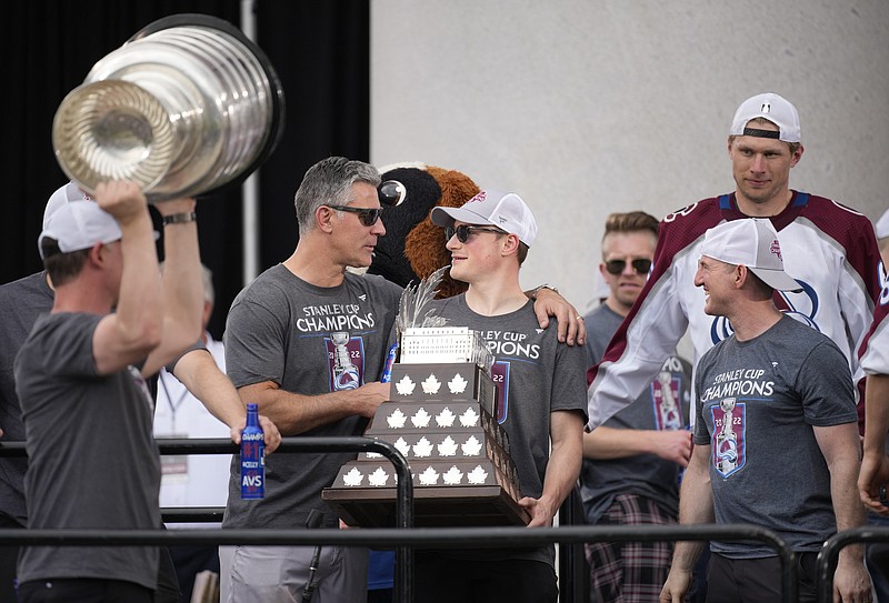 While assistant coach Nolan Pratt, left, lifts the Stanley Cup, Colorado Avalanche head coach Jared Bednar, second from left, congratulates defenseman Cale Makar, third from left, as skills coach Shawn Allard looks on during a rally outside the City/County Building for the NHL hockey champions after a parade through the streets of downtown Denver, Thursday, June 30, 2022. (AP Photo/David Zalubowski)