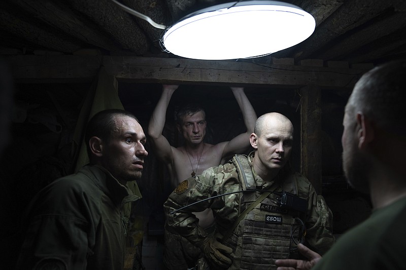 Ukrainian servicemen speak in the shelter at their position at the frontline near Kharkiv, Ukraine, on Saturday, July 2, 2022. (AP Photo/Evgeniy Maloletka)