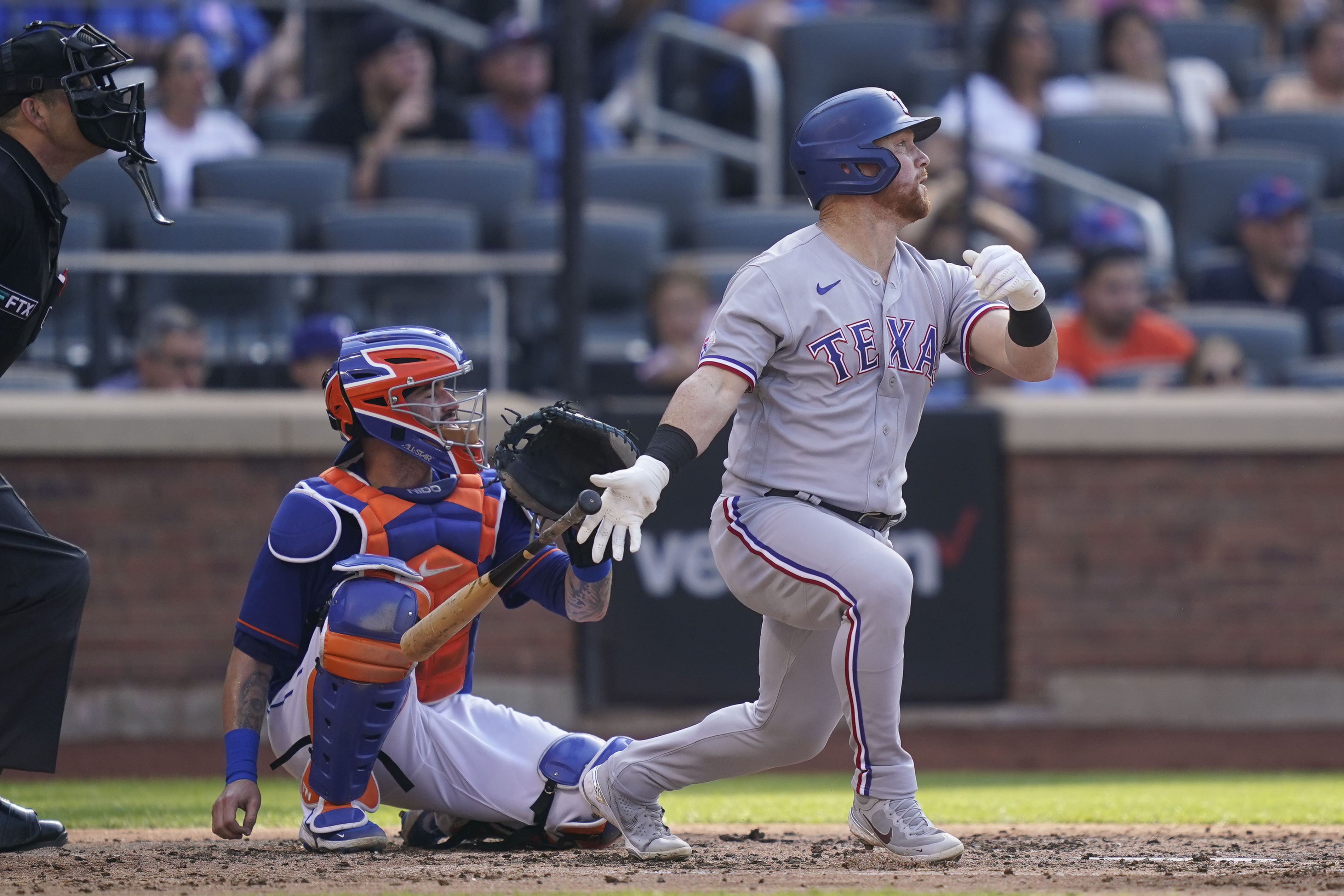 Texas Rangers' Kole Calhoun, right, celebrates with Texas Rangers' Adolis  Garcia, center, and Mitch Garver (18) after scoring a three run home run  off New York Mets starting pitcher Trevor Williams in