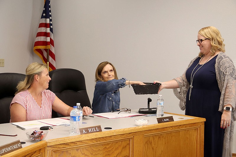 Farmington School Board member Lori Blew draws a piece of paper to decide her current term length from Kim Williamson, who serves in the administration office in human resources and as assistant to the superintendent. Blew will serve a five-year term. Board member Amy Hill (left) drew a four-year term.

(NWA Democrat-Gazette/Lynn Kutter)