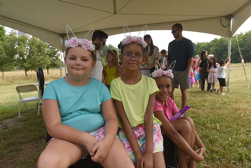 Caroline Weaver (from left), 7, Ciara Johnson, 8 and Tiara Johnson, 8, wait July 16 2022 for a ride in their wagon into the Firefly Fling Festival.
(NWA Democrat-Gazette/Flip Putthoff)