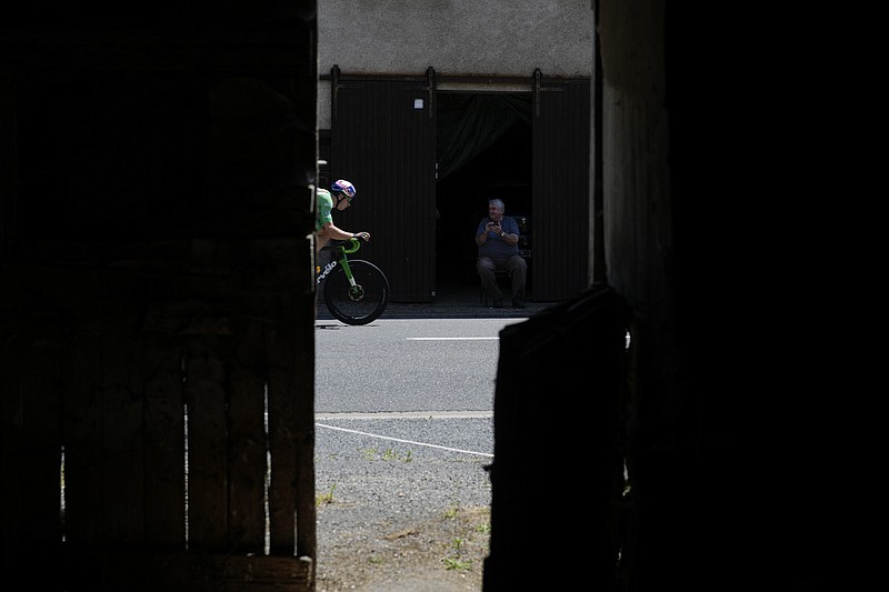 A spectator applauds for Belgium's Wout Van Aert, wearing the best sprinter's green jersey, who rides breakaway during the fifteenth stage of the Tour de France cycling race over 202.5 kilometers (125.5 miles) with start in Rodez and finish in Carcassonne, France, Sunday, July 17, 2022. (AP Photo/Thibault Camus)