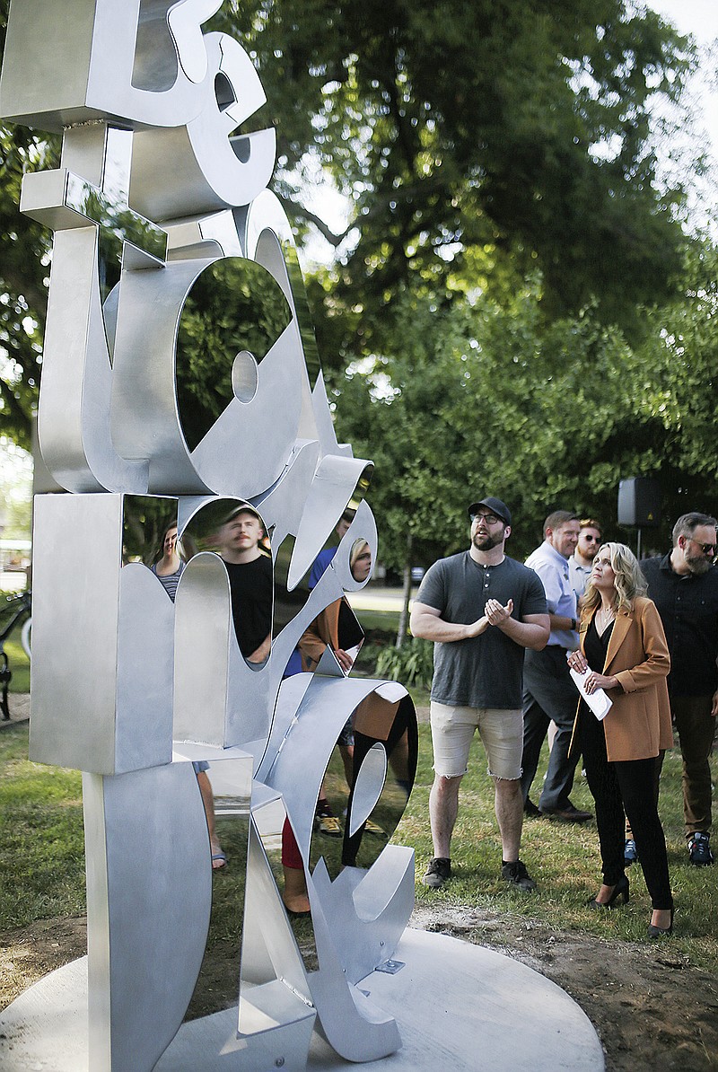 Bentonville Mayor Stephanie Orman (right) looks at the new sculpture “Found” on Thursday in Bentonville. “Found” is a 9-feet-tall sculpture consisting of different styles of letters that form “Bentonville” in a stacked jumble. Many letters have a polished steel face that will reflect the viewer. Visit nwaonline.com/220718Daily/ for today's photo gallery.

(NWA Democrat-Gazette/Charlie Kaijo)