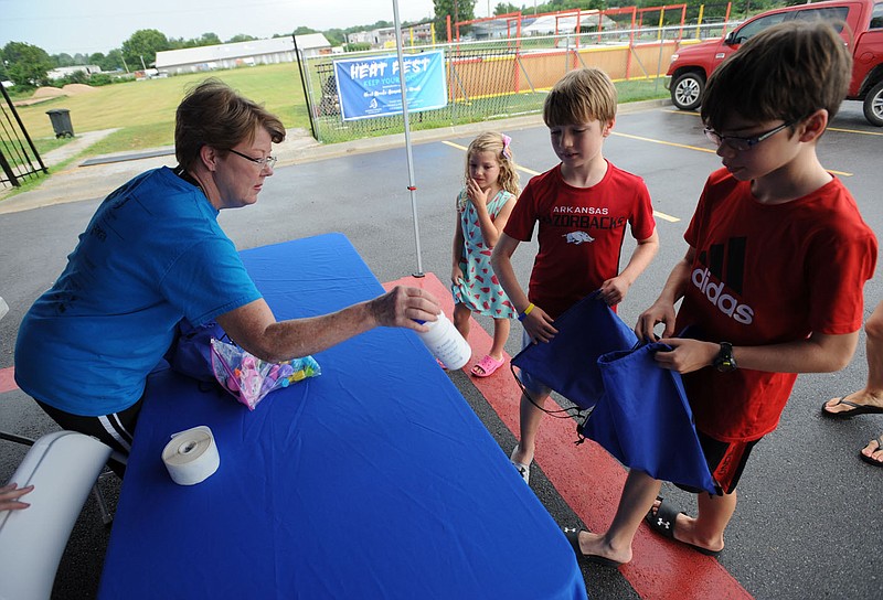NWA Democrat-Gazette/ANDY SHUPE
Volunteer Brenda Wheeley (from left) hands out water bottles Thursday, Aug. 1, 2019, to Emery Conner, 5; Bode Conner, 8; and Landon Conner, 11; all of Rogers, during Kendrick Fincher Hydration for Life's Heat Fest to kick off Heat Stroke Awareness Month at The Grove in Lowell. Kendrick Fincher Hydration for Life works to increase awareness for the importances of hydration and to prevent heat illness since its founding in 1996.