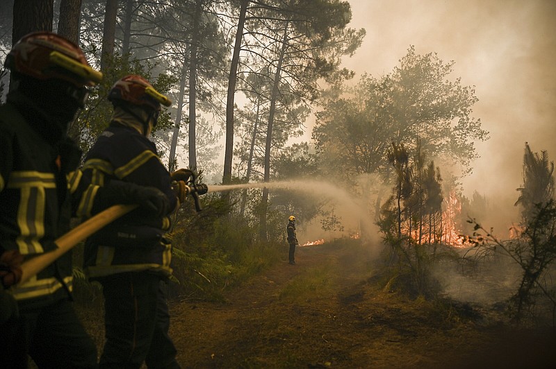 Firefighters puts water on a trees at a forest fire near Louchats, 35 kms (22 miles) from Landiras in Gironde, southwestern France, Monday, July 18, 2022. France scrambled more water-bombing planes and hundreds more firefighters to combat spreading wildfires that were being fed Monday by hot swirling winds from a searing heat wave broiling much of Europe. With winds changing direction, authorities in southwestern France announced plans to evacuate more towns and move out 3,500 people at risk of finding themselves in the path of the raging flames. (Philippe Lopez/Pool Photo via AP)