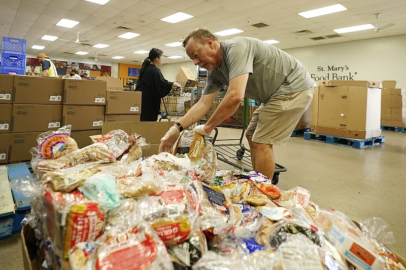 Voluntarios llenan carros de supermercado con alimentos para distribuirlos en el Banco de Alimentos St. Mary's, el miércoles 29 de junio de 2022, en Phoenix. (AP Foto/Ross D. Franklin)