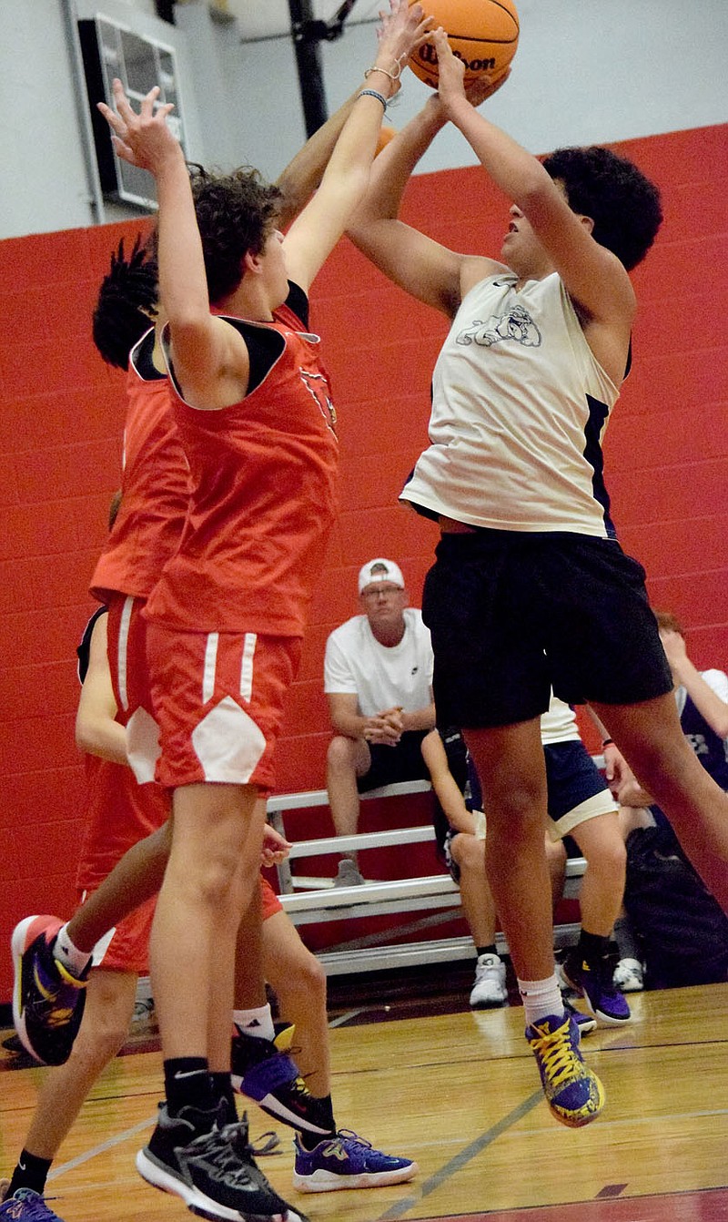 Westside Eagle Observer/MIKE ECKELS
Bulldog JJ Herrera (right) goes up over a Cardinal defender to drop in a field goal during the Ozark Catholic Academy's summer basketball contest between the Decatur Bulldogs and Farmington Cardinals A at AAO in Fayetteville July 20.