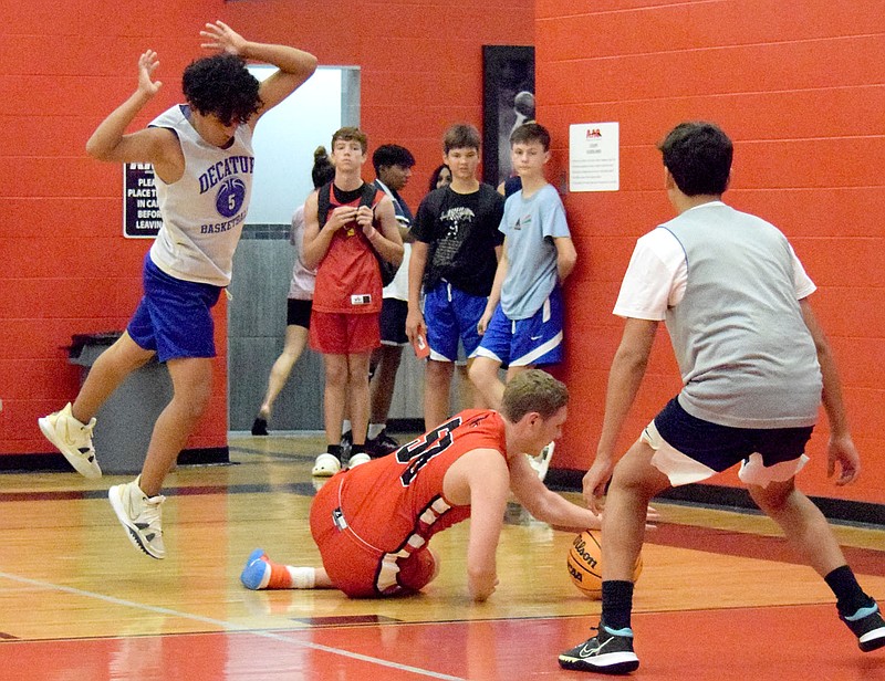 Westside Eagle Observer/MIKE ECKELS Brandon Cruz jumps up over a fallen Cardinal player to keep from tripping during the Decatur-Farmington A summer basketball camp contest in Fayetteville on July 20. The basketball event was hosted by the Tontitown-based Ozark Catholic Academy basketball program.