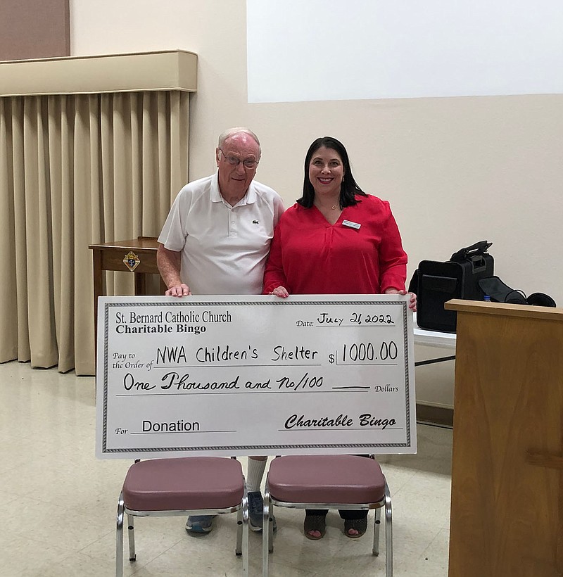 Tom Jurgens, representing charity bingo at St. Bernard Catholic Church in Bella Vista, presents a $1,000 check to Marlo Hamilton of the Northwest Arkansas Children’s Shelter. Charity bingo is played at 6:30 p.m. the third Thursday of every month St. Bernard’s Parish Hall, 1 St. Bernard Lane. (Courtesy photo)