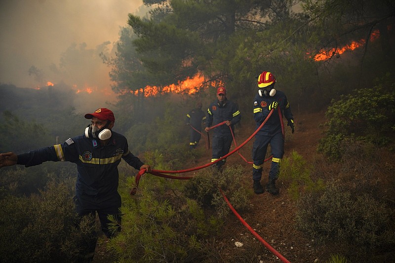 Firefighters struggle to extinguish a forest fire near the beach resort of Vatera, on the eastern Aegean island of Lesvos, Greece, Saturday, July 23, 2022. Locals were evacuated on Saturday as a wildfire threatened properties near a beach in the southern part of the island, which is also a popular tourist attraction. (AP Photo/Panagiotis Balaskas)