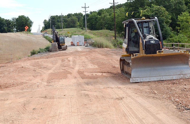 Westside Eagle Observer/MIKE ECKELS A red clay roadbed over the new Wolf Creek Bridge in northern Decatur is ready to be compressed by a roller machine and the bulldozer (right) in preparation for the asphalt overlay on July 22. The new bridge is expected to be complete sometime in the next three months.