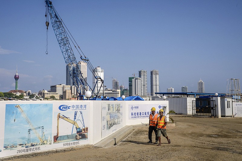 Workers walk past signs for the Colombo Port City, developed by China Harbour Engineering, a unit of China Communications Construction, in Colombo, Sri Lanka, on March 30, 2018. MUST CREDIT: Bloomberg photo by Atul Loke