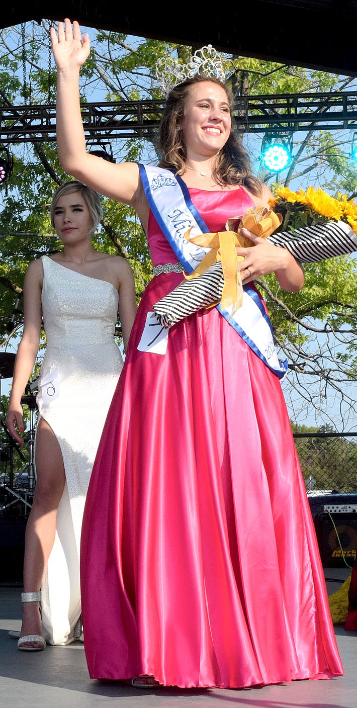 Westside Eagle Observer/MIKE ECKELS Kenzie Hill waves to the crowd after winning the 67th Miss Decatur Barbecue crown on Aug. 7, 2021. Who will be crowned the next Miss Decatur Barbecue? Come to the stage at Veterans Park in Decatur on Aug. 6 to find out.