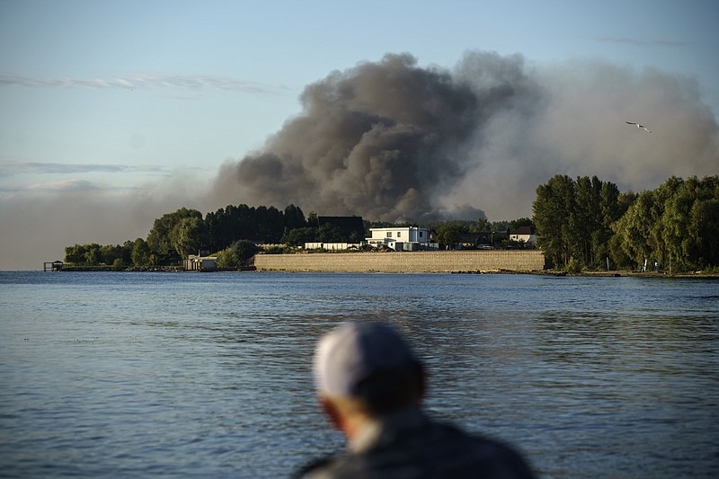 A fisherman watches smoke rise after Russian forces launched a missile attack on a military unit in the Vyshhorod district on the outskirts of Kyiv, Ukraine, Thursday, July 28, 2022. (AP Photo/David Goldman)