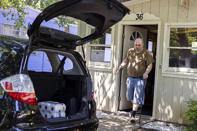Jeremy Ward unloads groceries from his car to his home in the Ridgeview Homes mobile home community in in Lockport, N.Y., June 23, 2022. Ward is one of the residents at Ridgeview participating in a rent strike after new owners of the park announced they were raising rents by six percent. "I moved here because it's basically the most affordable living," said Ward, who is disabled and living off of a fixed income. The plight of residents at Ridgeview is playing out nationwide as institutional investors, led by private equity firms and real estate trusts and sometimes funded by pension funds, swoop in to buy mobile home parks. (AP Photo/Lauren Petracca)