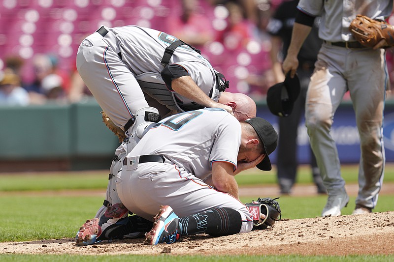 Miami Marlins catcher Jacob Stallings, left, checks on starting pitcher Daniel Castano after he was hit by a line drive by Cincinnati Reds' Donovan Solano during the first inning of a baseball game Thursday, July 28, 2022, in Cincinnati. (AP Photo/Jeff Dean)