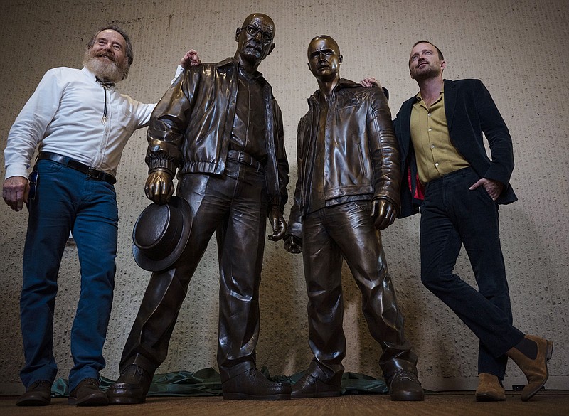 Bryan Cranston, left, and Aaron Paul, right, pose for photos next to statues of their characters during the "Breaking Bad" unveiling event in downtown Albuquerque, N.M., on Friday July 29, 2022. (Chancey Bush/The Albuquerque Journal via AP)