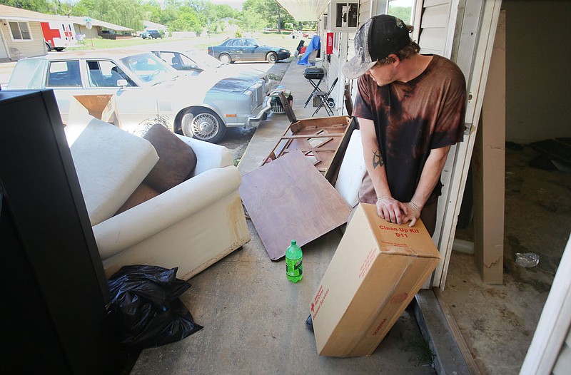 Residents move out damaged belongings on May 2, 2017, from West End Apartments in Fayetteville. The city government is considering buying the apartments with a $1.4 million asking price in order to demolish the structure, which consistently floods during severe rain events. (File photo/NWA Democrat-Gazette/David Gottschalk)