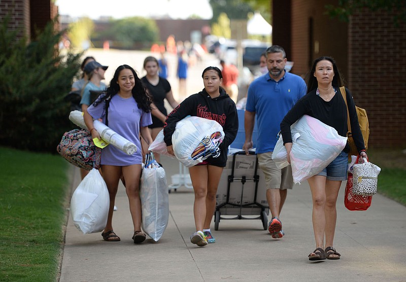 Volunteers help first-year University of Arkansas students and their families on Aug. 12, 2021, to move into dormitory rooms at the Northwest Quad complex on the university campus in Fayetteville. University administrators anticipate all 6,500 beds available to freshmen will be full this fall, with an additional 900 or so beds needed at off-campus student complexes that will be considered university housing. (File photo/NWA Democrat-Gazette/Andy Shupe)