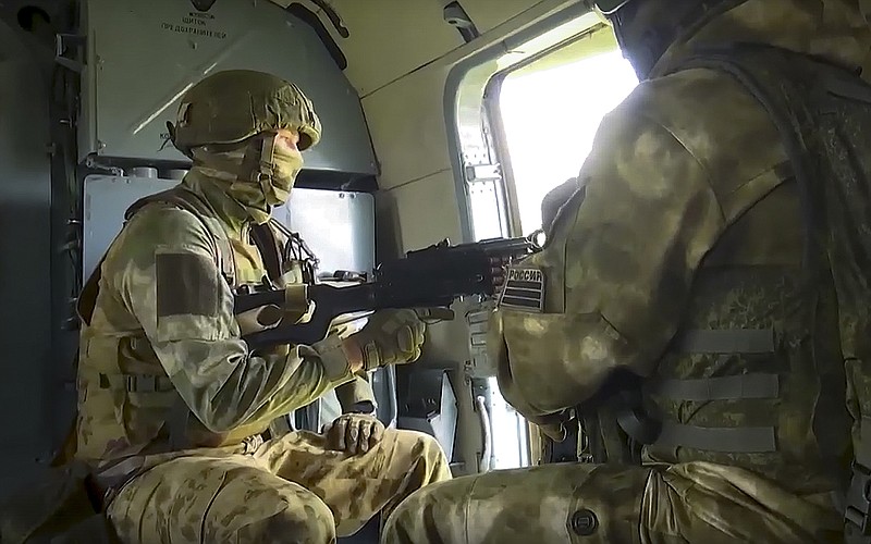 In this handout photo taken from video and released by Russian Defense Ministry Press Service on Saturday, July 30, 2022, Russian Army soldiers get ready to fight on a board of a military helicopter during a mission at an undisclosed location in Ukraine. (Russian Defense Ministry Press Service via AP)