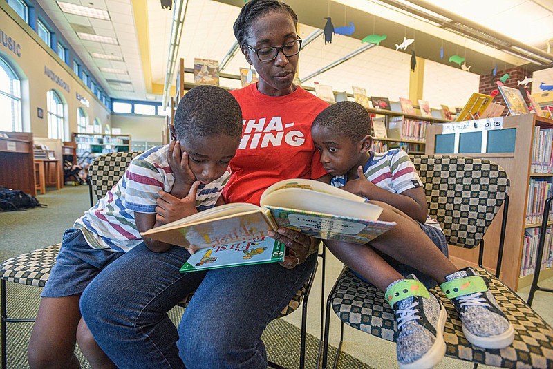 Joelle Yamkam of Fort Smith reads to her sons Aviel Yamkam (left) and Aziel Yamkam, both 4, during a weekly story time and crafts event hosted at the Fort Smith Dallas Street Library. (NWA Democrat-Gazette/Hank Layton)