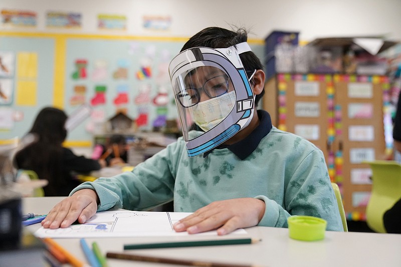 A student wears a mask and face shield in a fourth-grade class on Jan. 12, 2022, at Washington Elementary School in Lynwood, Calif. As a new school year approaches, COVID-19 infections are again on the rise, fueled by highly transmissible variants, filling families with dread. They fear the return of a pandemic scourge: outbreaks that sideline large numbers of teachers, close school buildings and force students back into remote learning. (AP Photo/Marcio Jose Sanchez, File)