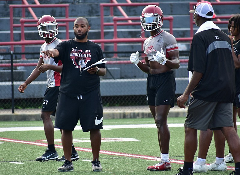 Pine Bluff High School Coach Micheal Williams (second from left) instructs wide receivers along with receivers and quarterbacks coach Ryan Stinson during practice Monday at Jordan Stadium. (Pine Bluff Commercial/I.C. Murrell)